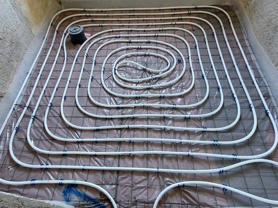Schneckenförmig verlegte Fußbodenheizung mit Bodenablauf in einem Raum im Rohbau