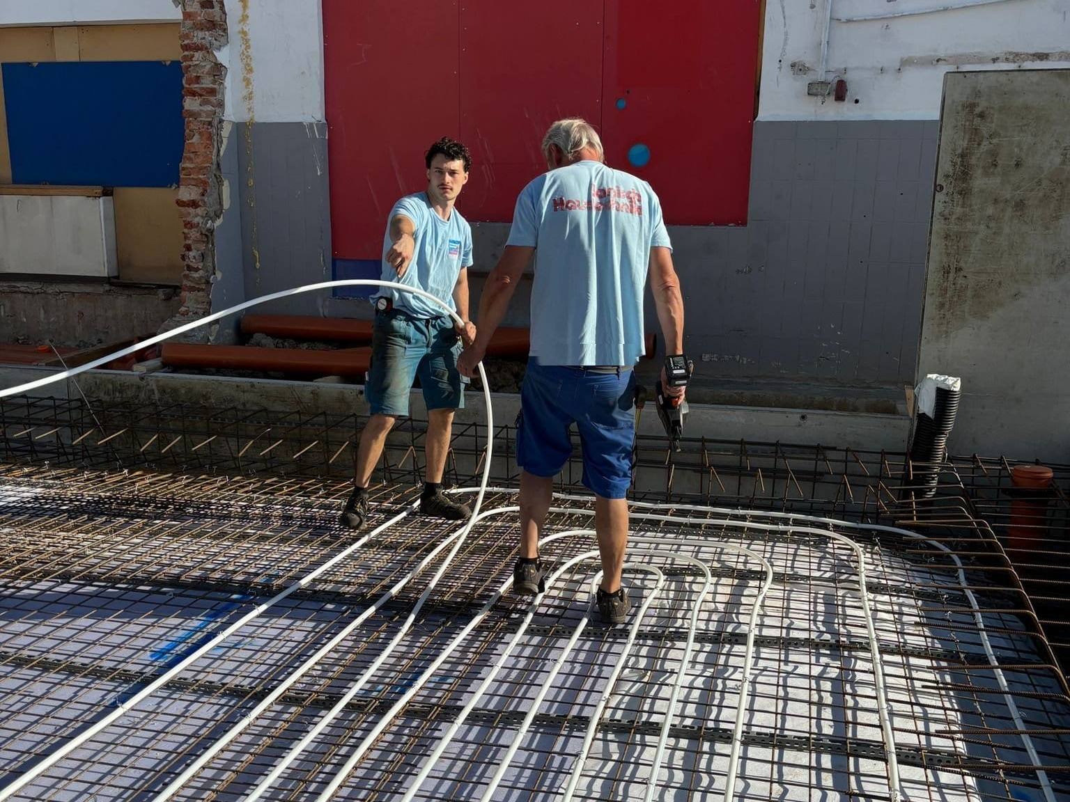 Zwei Janisch-Monteure verlegen die Rohre der Betonkernaktivierung auf der Bewehrung