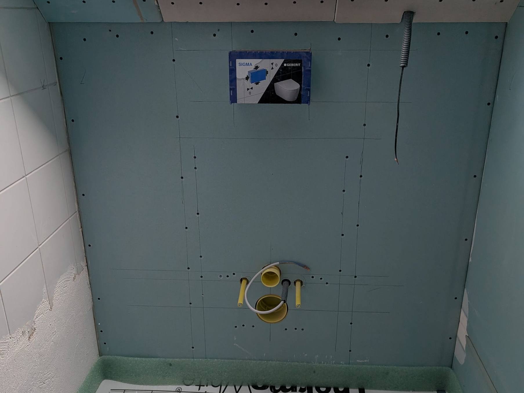 WC-Vorwand im Rohbau mit Geberit-Abdeckung und Anschlüssen unter einem Dachfenster