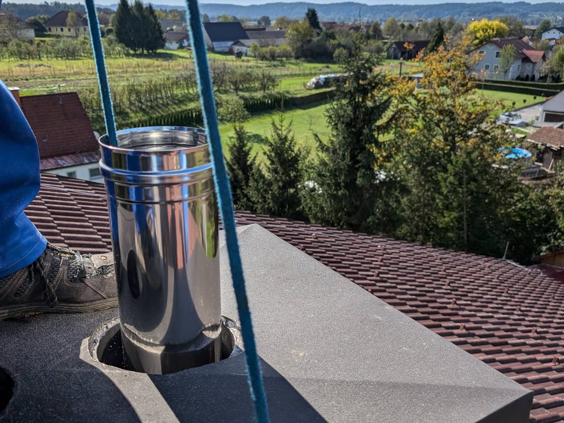 Edelstahl-Abgasrohr in der Kaminabdeckung auf einem Ziegeldach, eingezogen von Janisch Haustechnik
