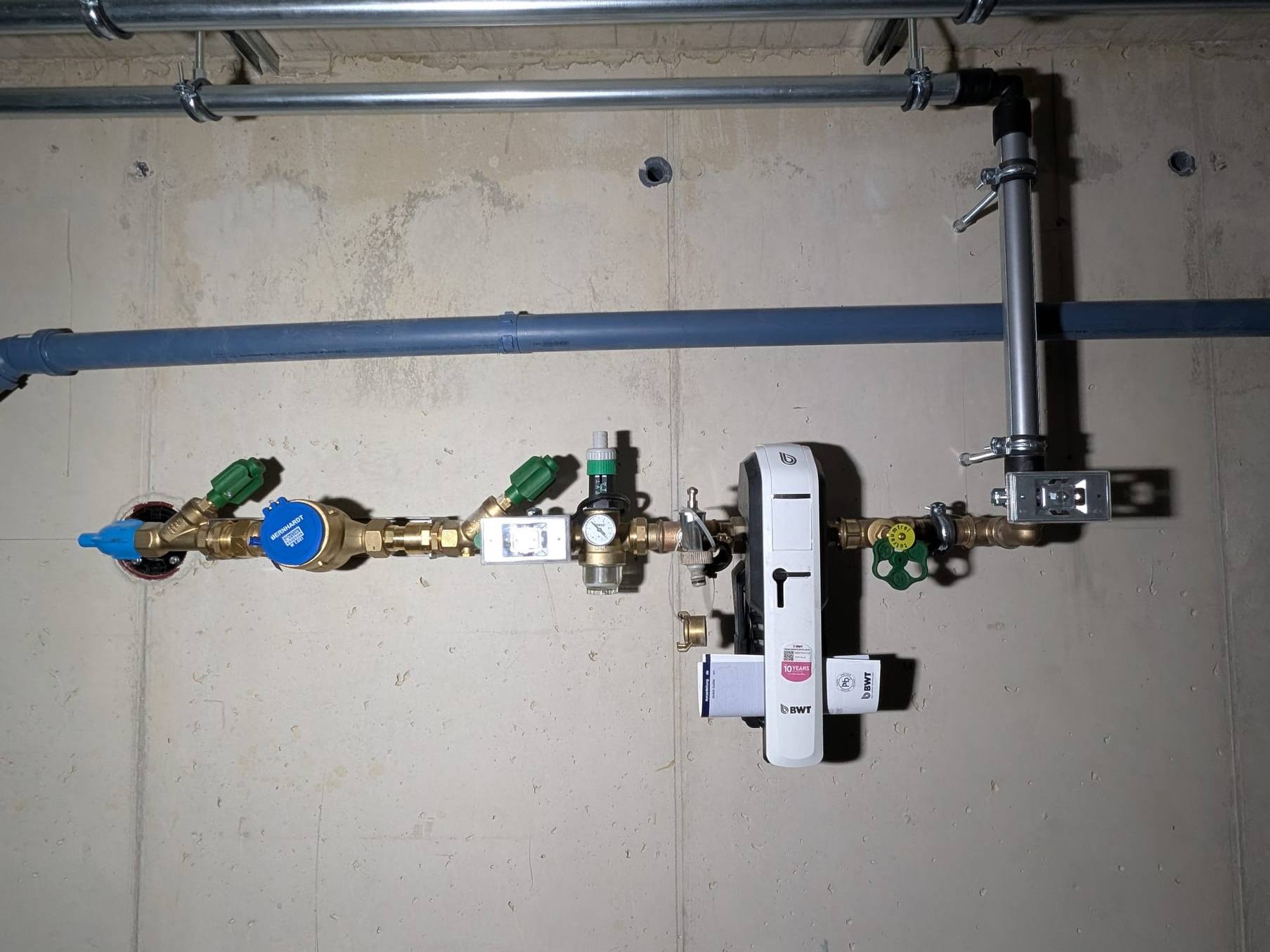 Neu montierte Hauswasserleitung mit Filter und Absperrventilen an einer Betonwand