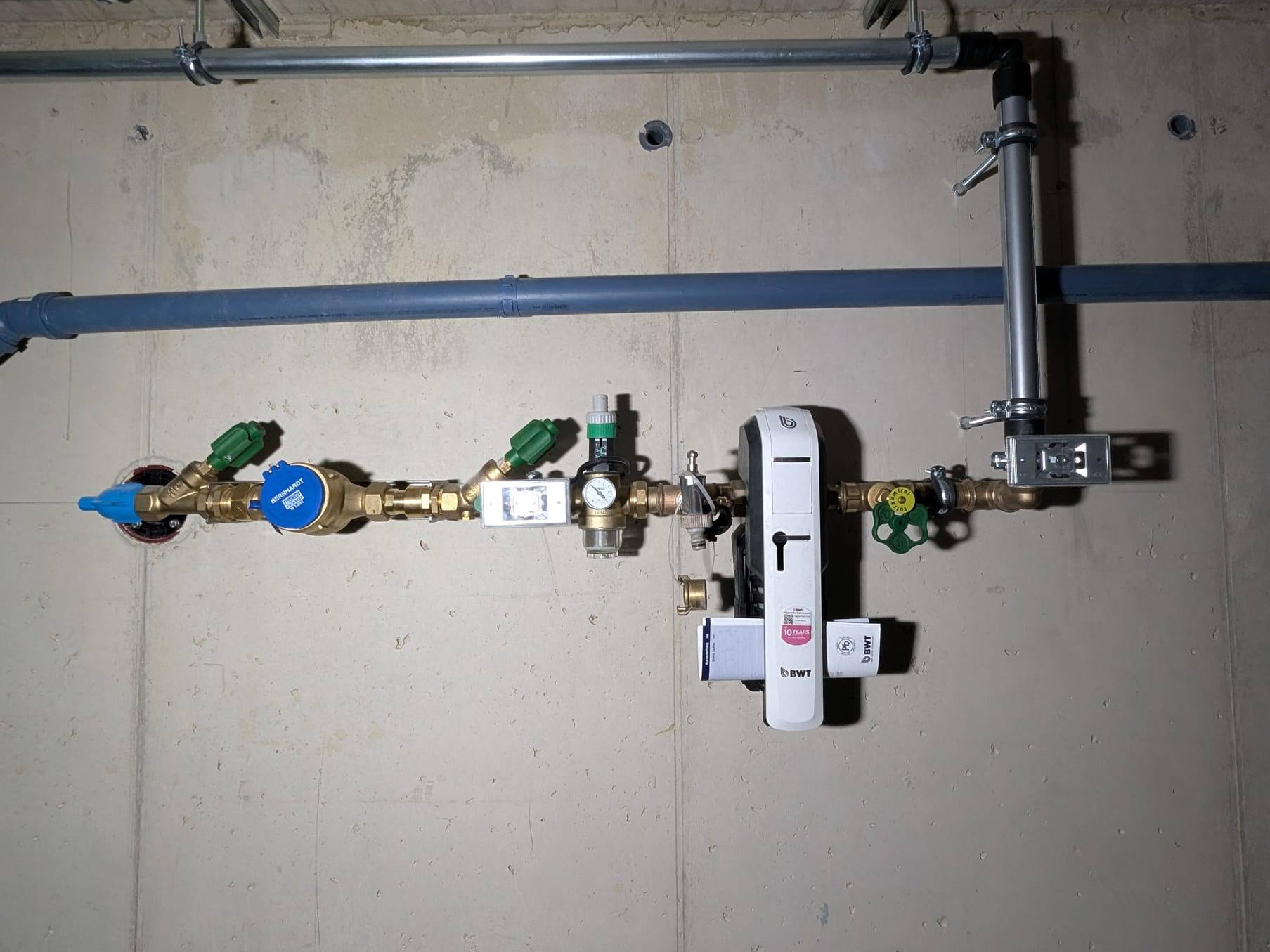 Hauswasseranschluss mit Wasserzähler, Druckminderer und BWT-Gerät an einer Betonwand