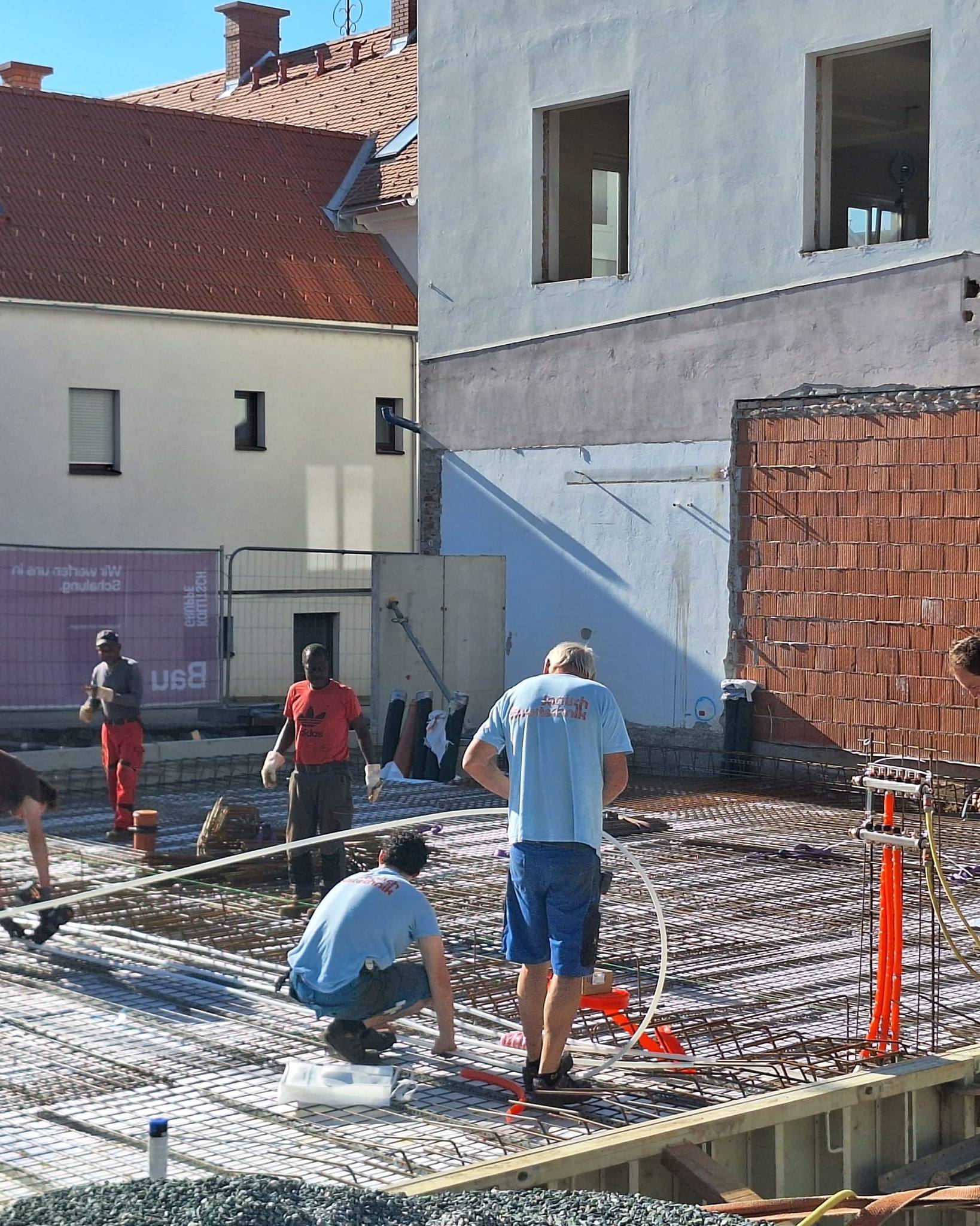 Monteure verlegen die Rohre der Betonkernaktivierung auf der Bewehrung vor dem Altbau