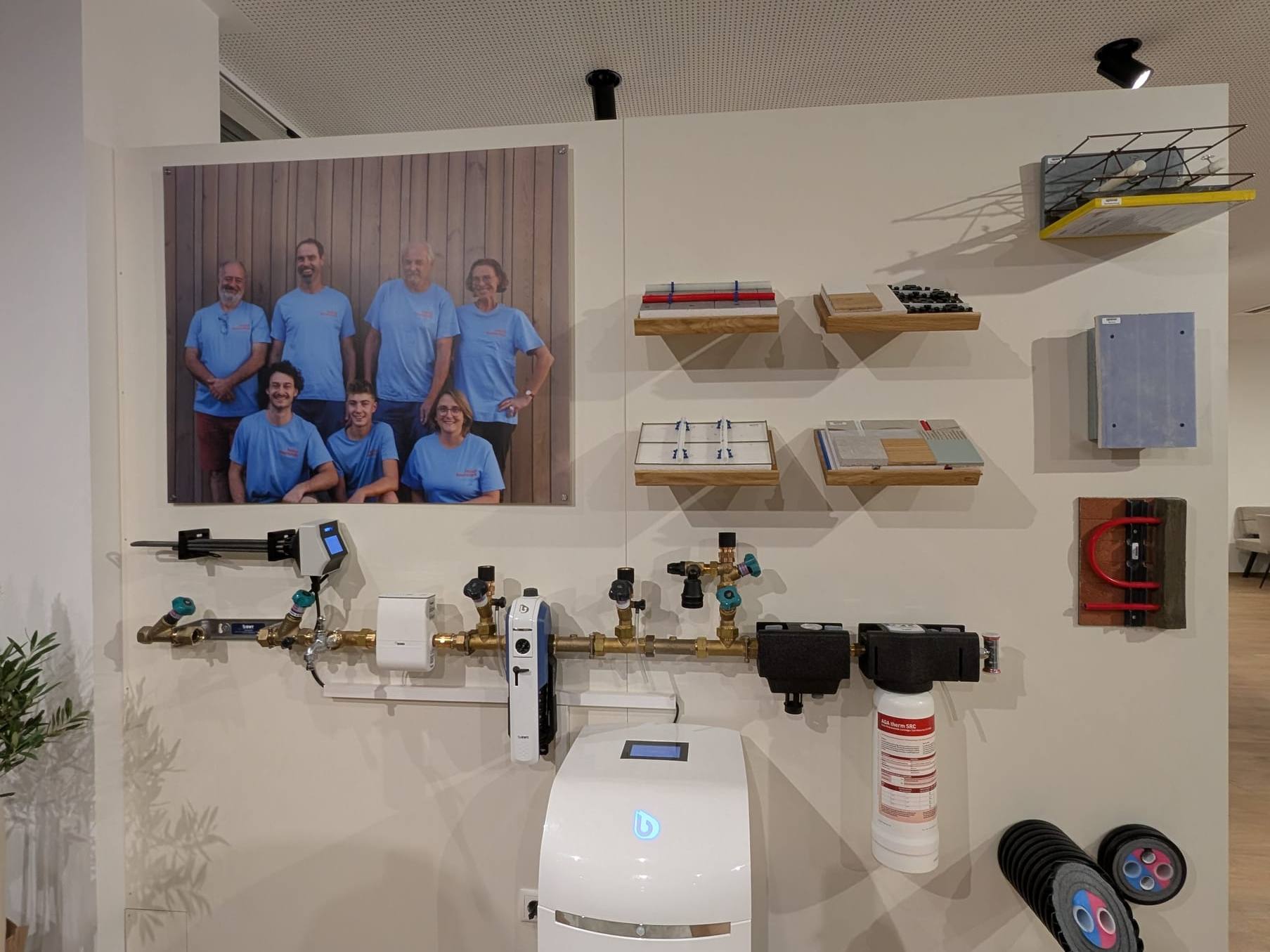 BWT-Trinkwasserlinie mit Filter und Enthärtungsanlage an einer weißen Wand, daneben ein Teamfoto