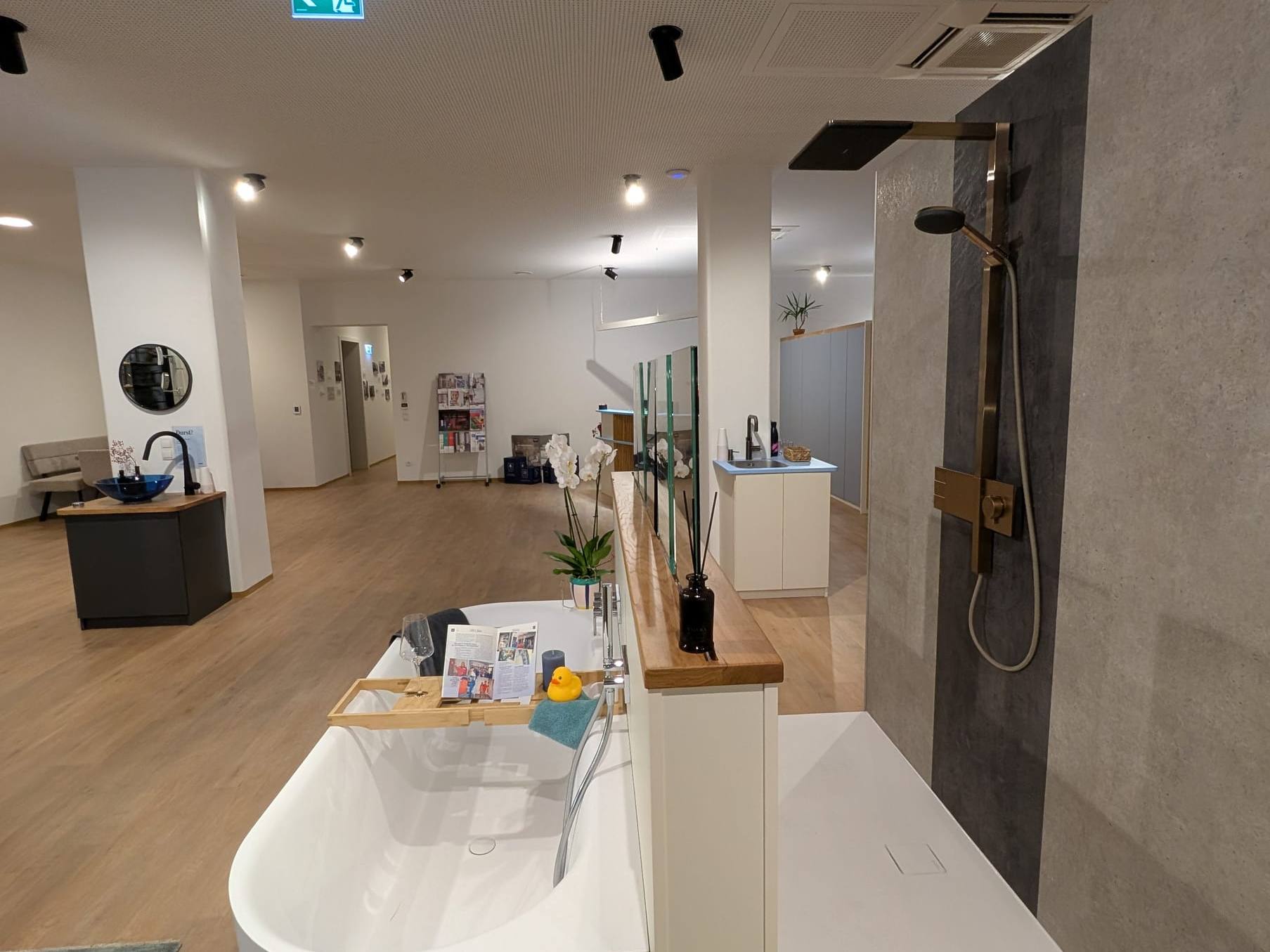 Freistehende Badewanne vor einer Duschwand im Schauraum