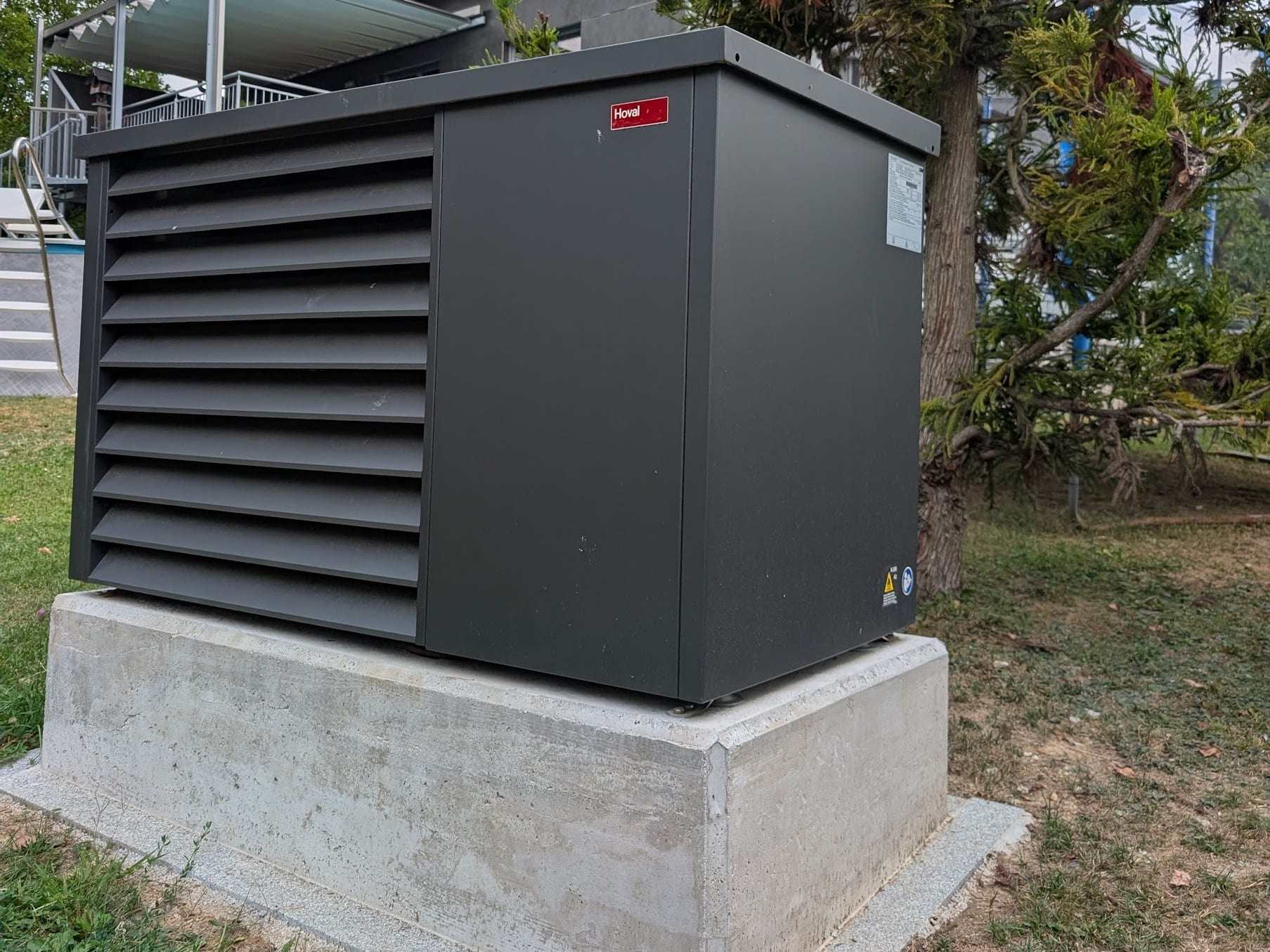 Luft/Wasser-Wärmepumpe von Hoval auf einem durchgehenden Betonsockel im Garten