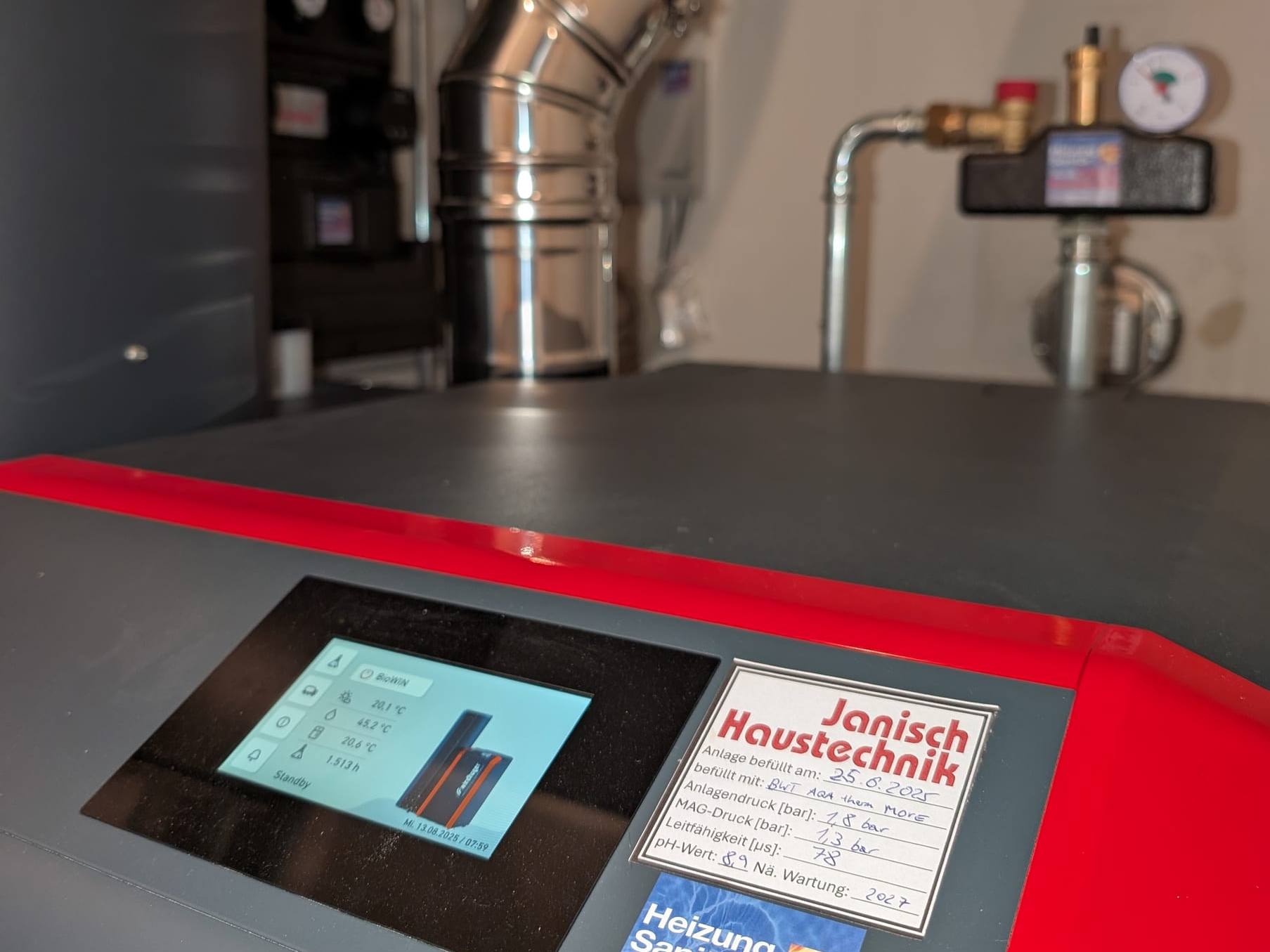 Pelletskessel mit Touch-Display und Kundendienst-Aufkleber von Janisch Haustechnik