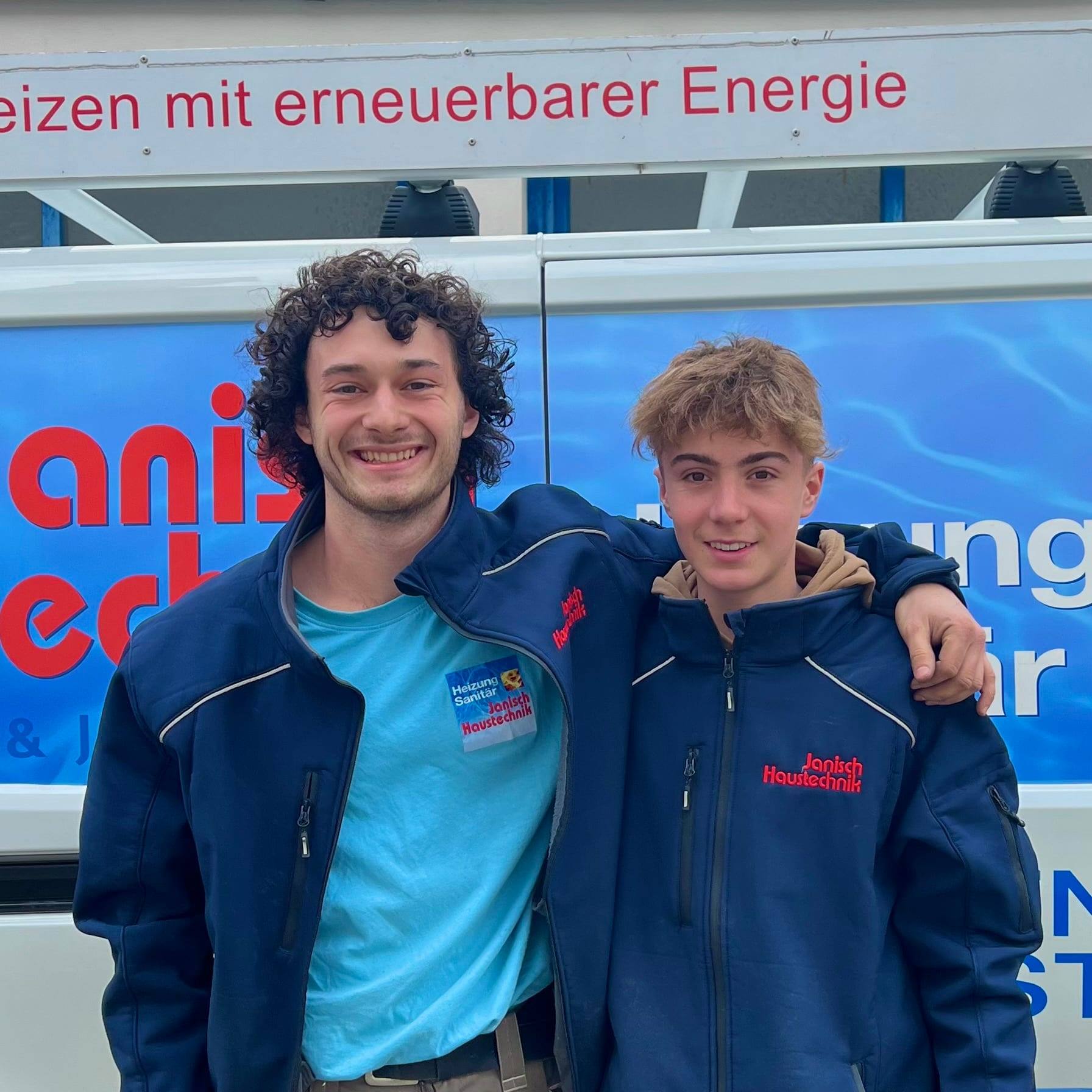 Die Lehrlinge Silvan Tesar und Jannik Gerstmann Arm in Arm vor einem Servicebus von Janisch Haustechnik