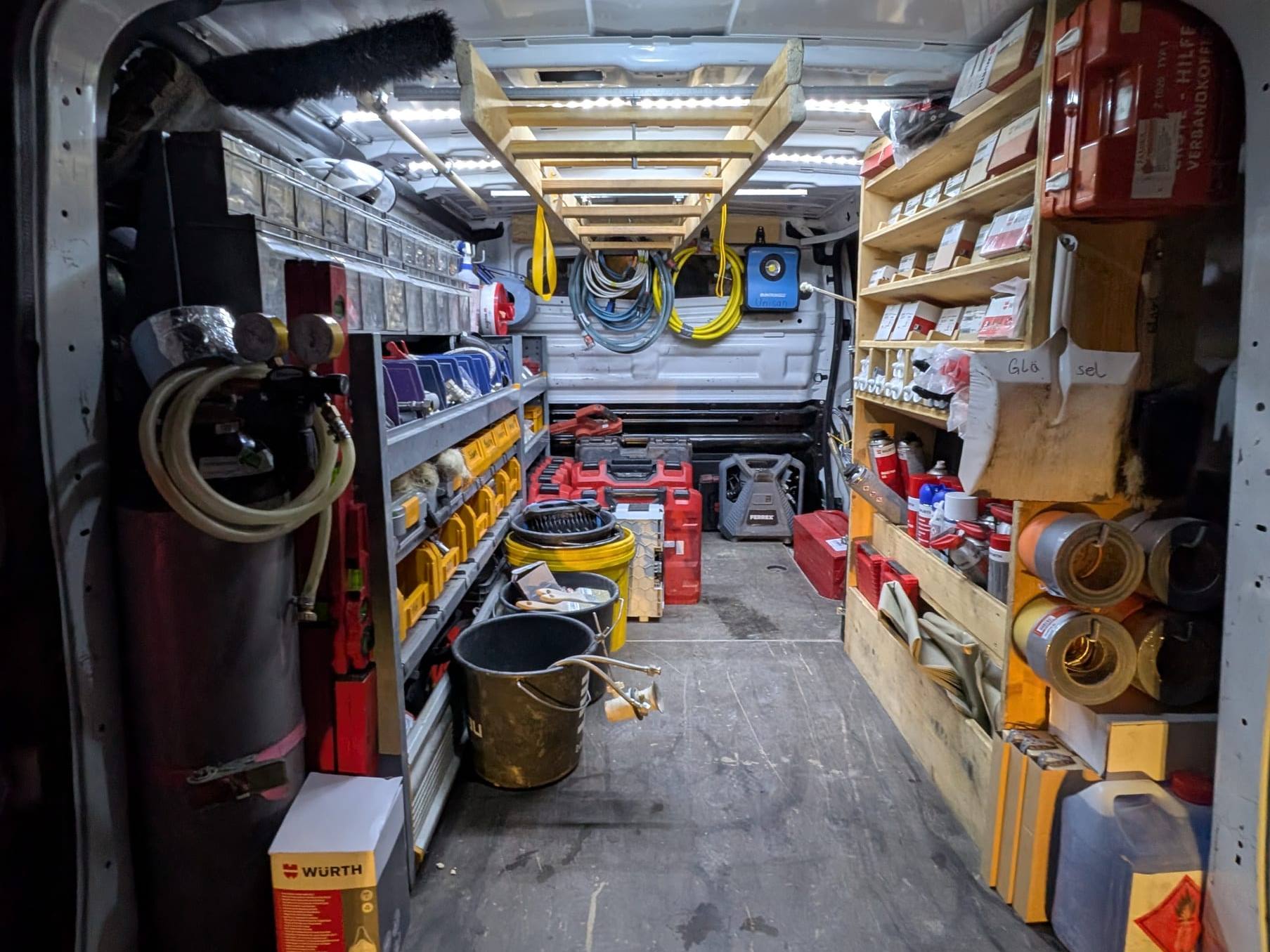 Blick in den Laderaum eines Servicebusses mit Regalen voller Ersatzteile, Sortimentskästen und Werkzeugkoffern