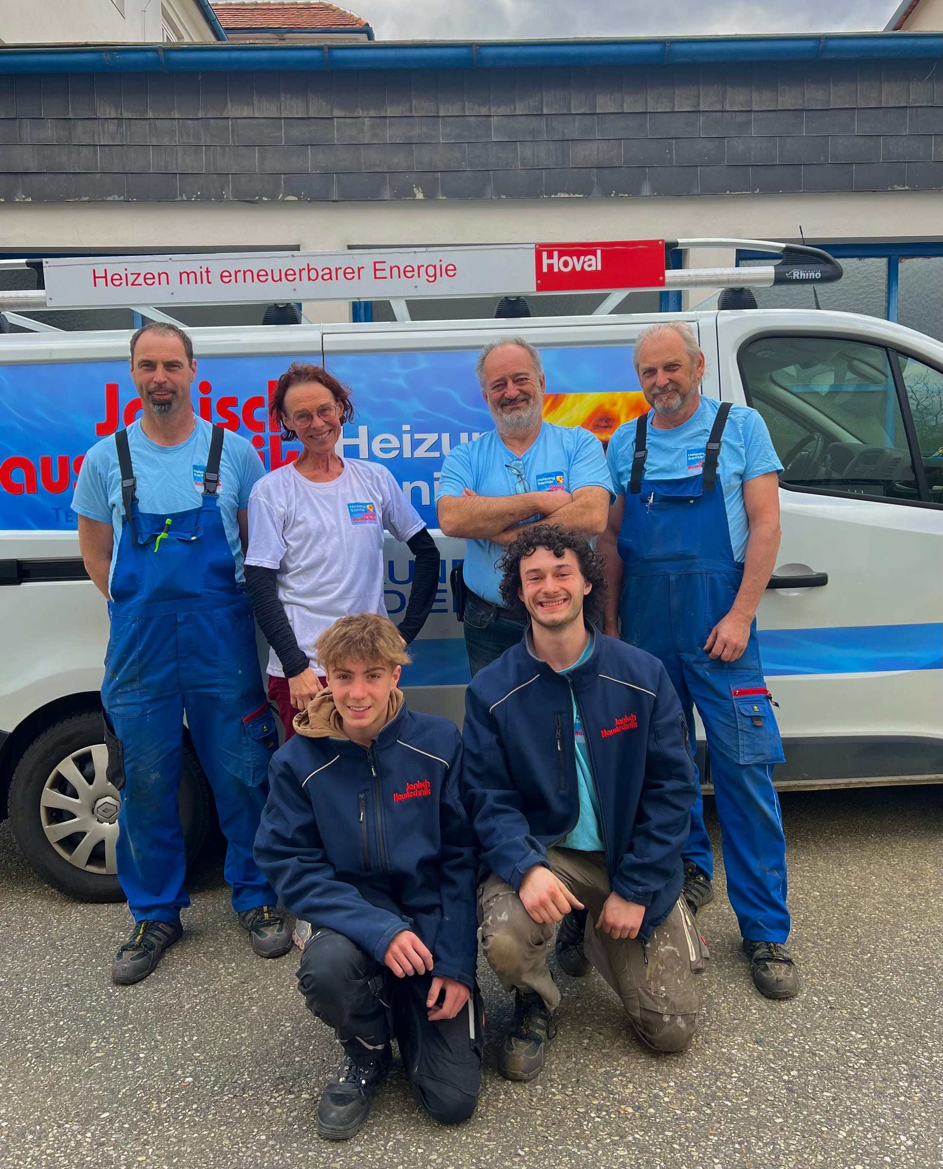 Das Team von Janisch Haustechnik in Arbeitskleidung vor dem Kundendienst-Bus, vorne kniend die beiden Lehrlinge