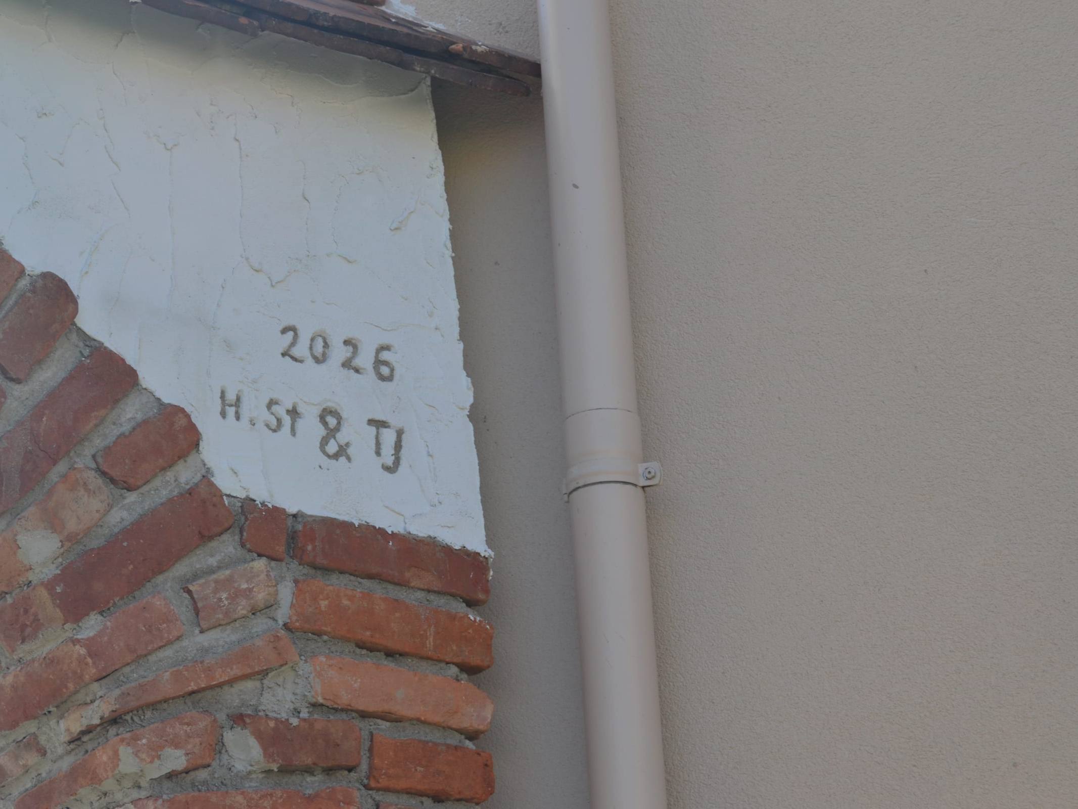 Alter Ziegel in der Wand mit eingeritzter Jahreszahl 2026 und Initialen